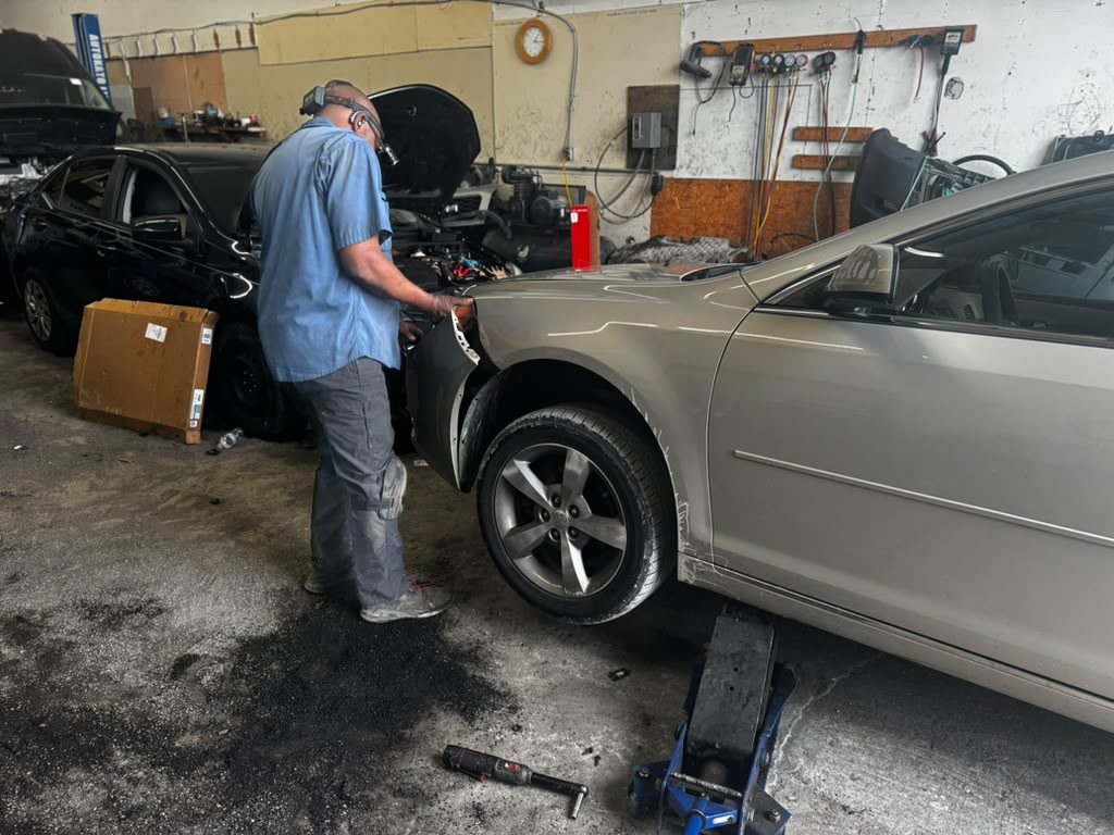Technician repairing the front fender of a gold sedan